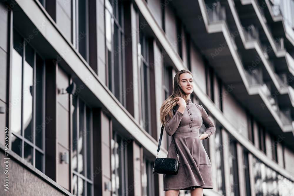 Fototapeta premium A young girl walks near the office with a handbag on her shoulder