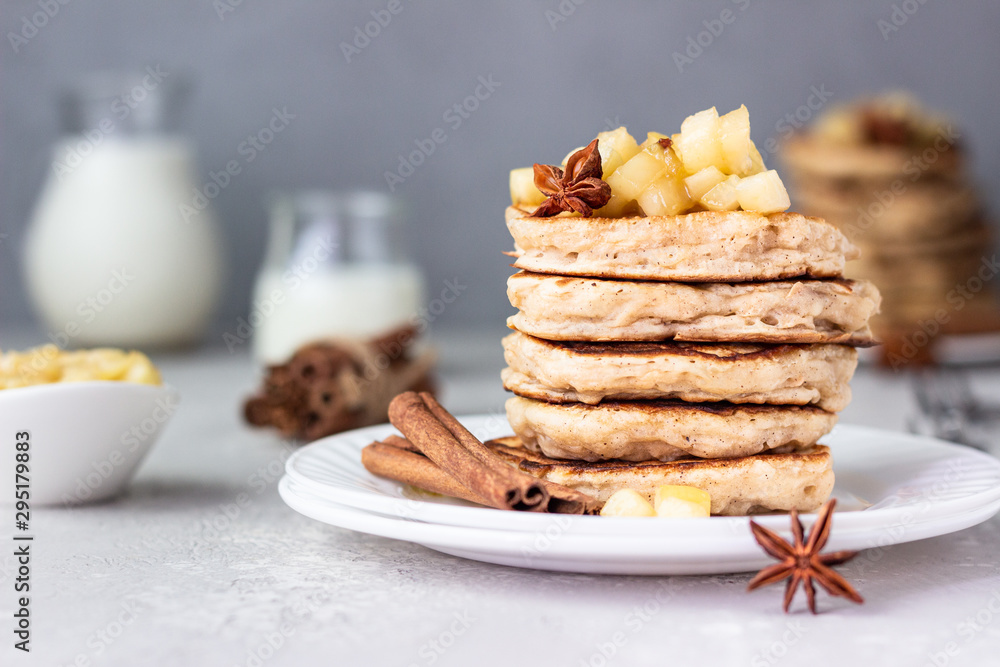 Stack of delicious sweet and spicy apple pancakes with fried caramelized apples and spices (anise and cinnamon) on a white plate. Autumn breakfast. Stack of delicious sweet and spicy apple pancakes with fried caramelized apples and spices (anise and cinnamon) on a white plate. Autumn breakfast.