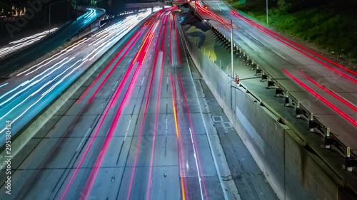 Motion time-lapse or hyper-lapse of cars in traffic on a Los Angeles freeway with streaks of blurred head lights and red tail lights.