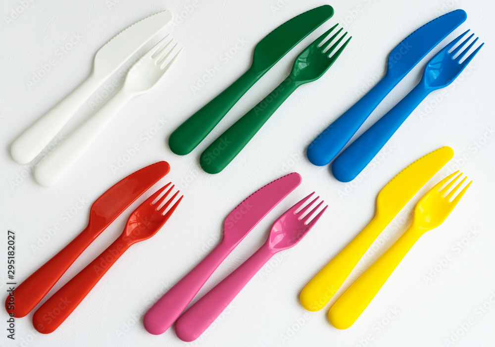Colored bright plastic dishes beautifully laid out on a white background. Knives, forks, spoons. Menu concept for bar and restaurant. Free space for text. Colored bright plastic dishes beautifully laid out on a white background. Knives, forks, spoons. Menu concept for bar and restaurant. Free space for text.