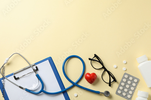 Stethoscope and medicines on yellow background, top view. Doctor workplace photo