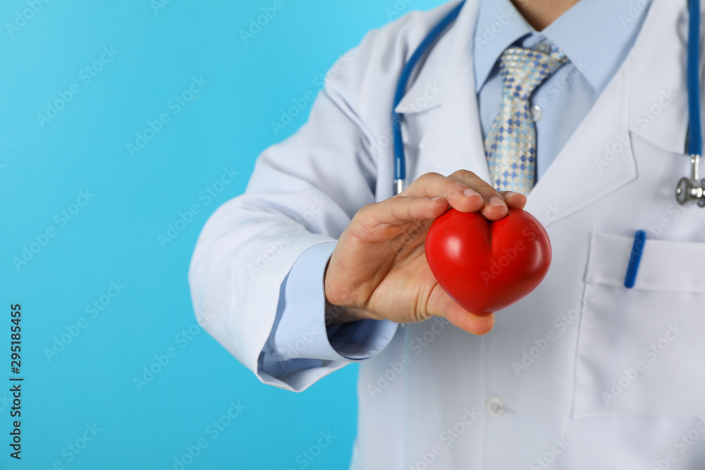 Doctor with stethoscope and heart against blue background, copy space Doctor with stethoscope and heart against blue background, copy space