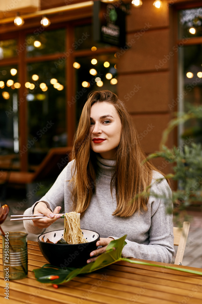 Young european girl eating ramen