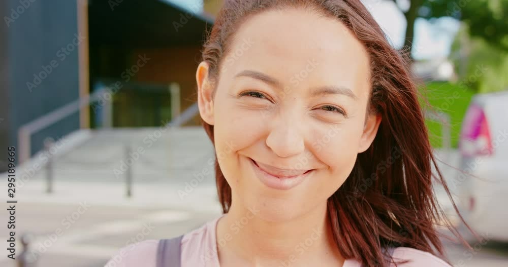 A young dark-haired lady smiling outdoors A young dark-haired lady smiling outdoors