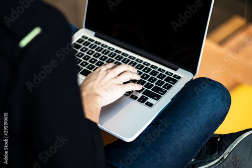 Back view of a young student typing on her laptop sitting with her legs crossed. Close up on technology. Blogger and applications