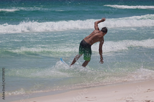 Skim boarder in the beach surf with splashing water