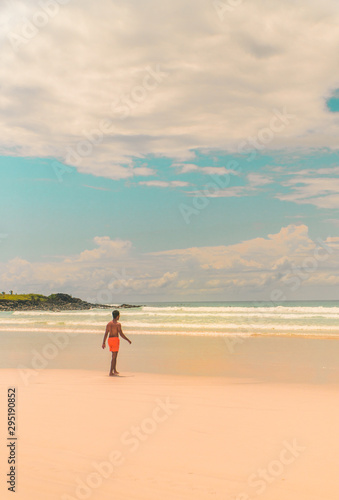 Man tourist on Galapagos beach. Tourist man walking along Tropical beach with turquoise ocean waves and white sand. Sand bay view. Holiday, vacation, paradise, summer vibes. Shot in Isabela, San Crist