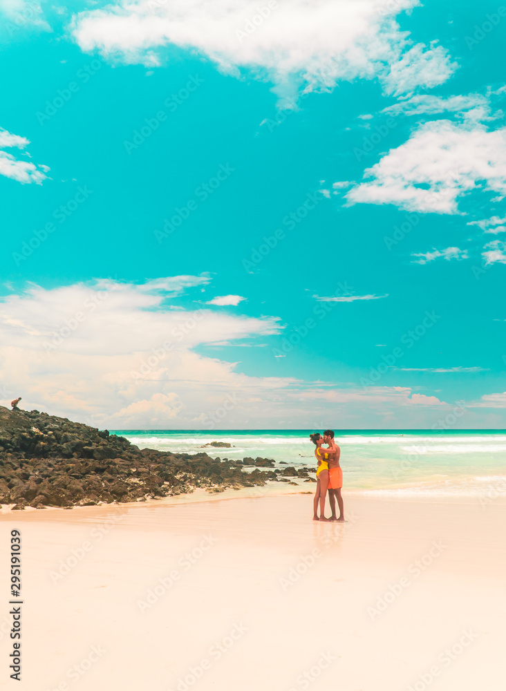 Couple kissing beach holiday romance. Tourist on Tropical beach with turquoise ocean waves and white sand. Sand bay view. Holiday, vacation, paradise, summer vibes. Isabela, San Cristobal Couple kissing beach holiday romance. Tourist on Tropical beach with turquoise ocean waves and white sand. Sand bay view. Holiday, vacation, paradise, summer vibes. Isabela, San Cristobal