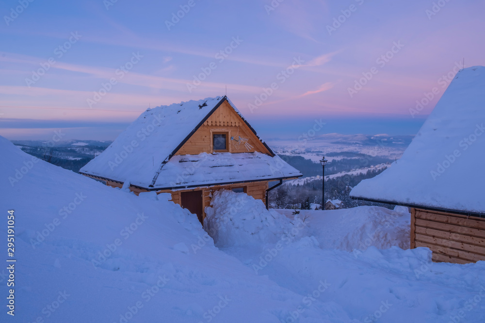 Small wooden village in mountains covered by snow.