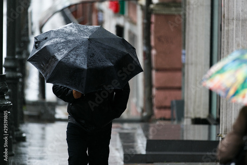 A man with an umbrella is hiding from strong winds and rain