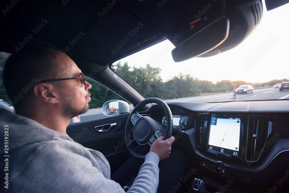 Man driving a car. Success in motion. Handsome young man driving a car. A man holds the steering wheel of a car.