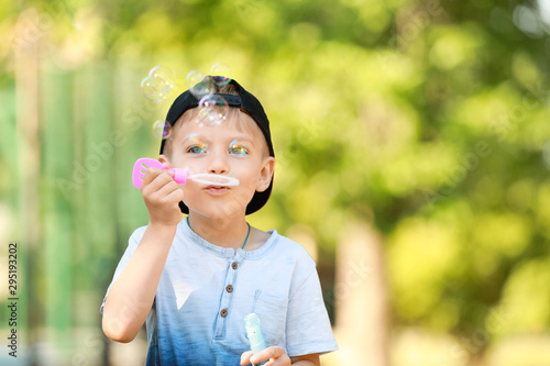 Cute little boy blowing soap bubbles in park