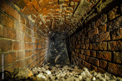 Old collapsed red brick underground vaulted historical sewer tunnel, selective focus