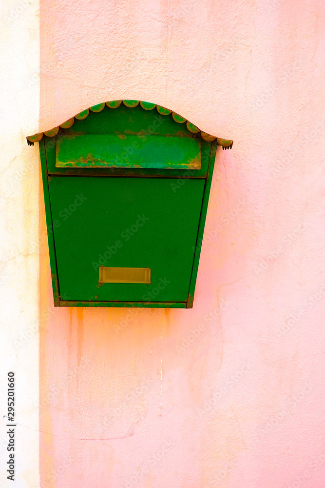 Weathered green letter box or mailbox on a pink wall.