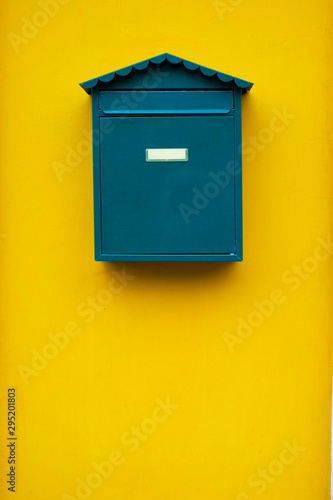 Elegant simple green mail box on a yellow wall.