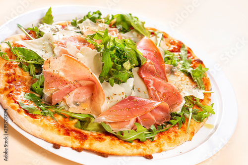 Italian Cuisine. Pizza with prosciutto, ham, arugula and parmesan