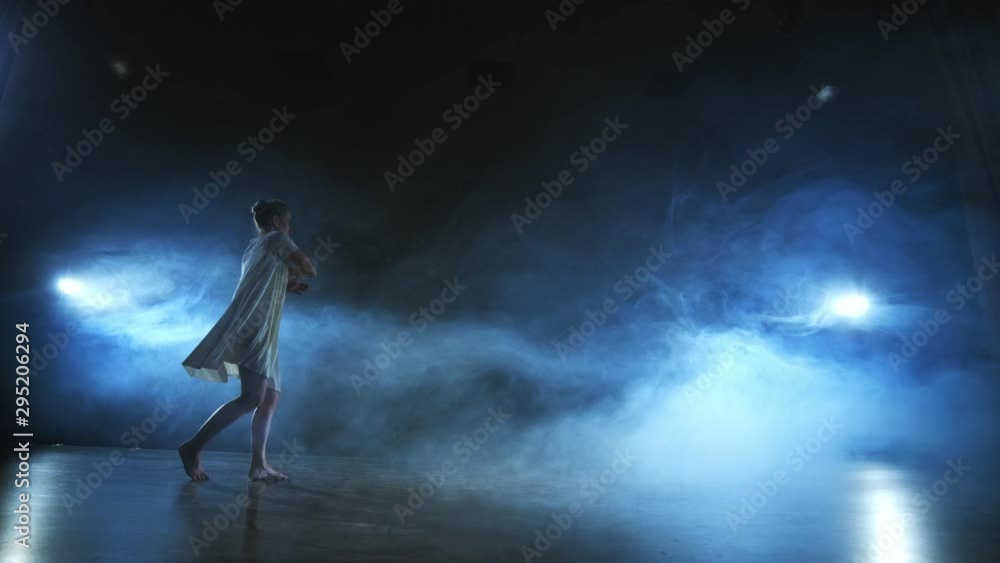 Modern ballet dancing woman barefoot doing spins and pirouettes and dance steps standing on stage in smoke in slow motion. Performance on stage Modern ballet dancing woman barefoot doing spins and pirouettes and dance steps standing on stage in smoke in slow motion. Performance on stage