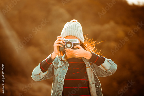 Asian woman in blue shirt with vintage film camera travel alone on the mountain and take photo in sunset summer time travel concept for one woman