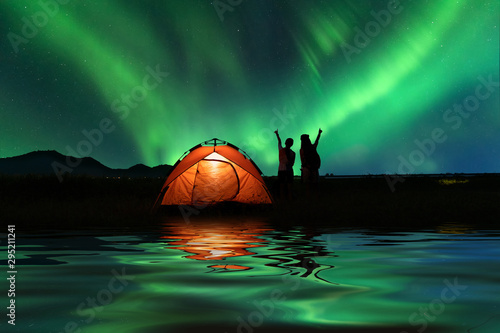 Two Asian girls outdoor camping outdoor on Holiday with  majestic Northern lights . Vacation ,Camping ,Travel  Concepts.