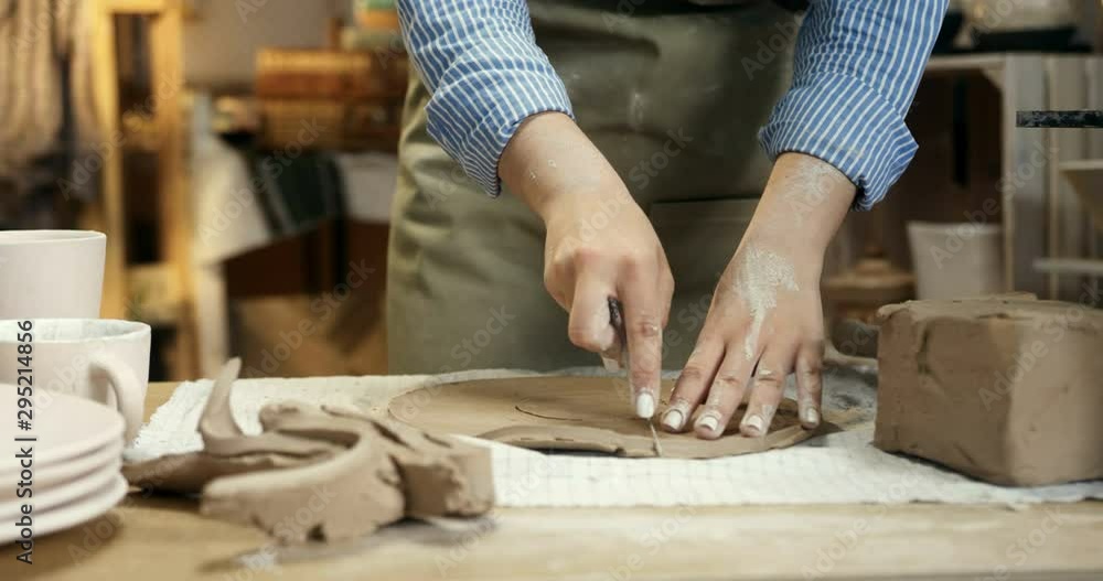 Close up of the hands of the female Caucasian potter dividing a clay in two parts for molding a ceramic item from it. Close up of the hands of the female Caucasian potter dividing a clay in two parts for molding a ceramic item from it.