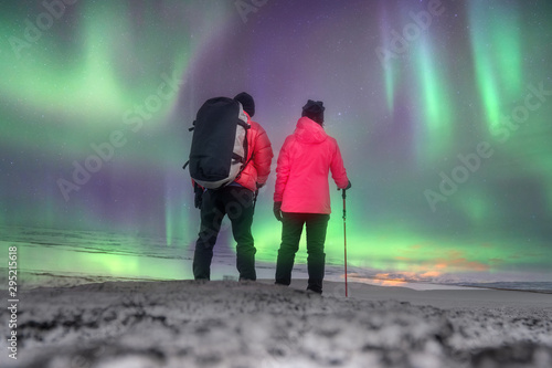 Asian couple hiking on mountain holiday on snow mountain and Aurora light ,Iceland .success, winner, leader and Teamwork concept .