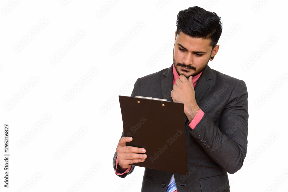 Portrait of young handsome Indian businessman holding clipboard Portrait of young handsome Indian businessman holding clipboard