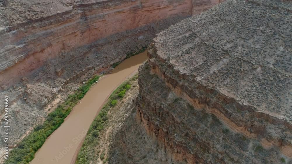 Inspirational drone flight over the bend of winding Colorado river stretching in ancient canyon, which is made of erosion geological layers. Muddy water of the river is surrounded with rocky shores Inspirational drone flight over the bend of winding Colorado river stretching in ancient canyon, which is made of erosion geological layers. Muddy water of the river is surrounded with rocky shores