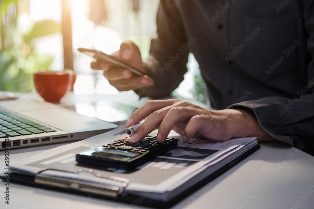 Businessman calculates financials with graph paper on the table on the cost of home office in the evening. Businessman calculates financials with graph paper on the table on the cost of home office in the evening.