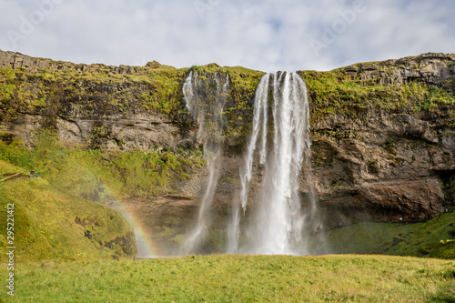 Seljalandsfoss waterfall drops from cliffs that allow people to walk behind the falls in Southern Iceland