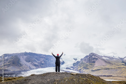 Woman with raised arms looks out to Vatnajokull Glacier in Iceland