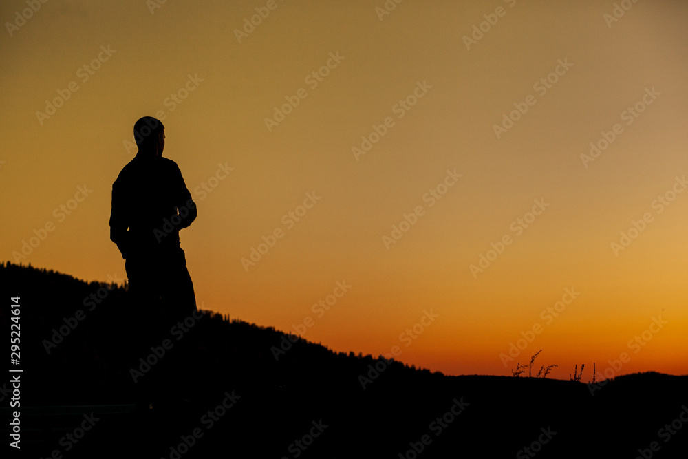 A young successful man looks at the sunset. Silhouette.
