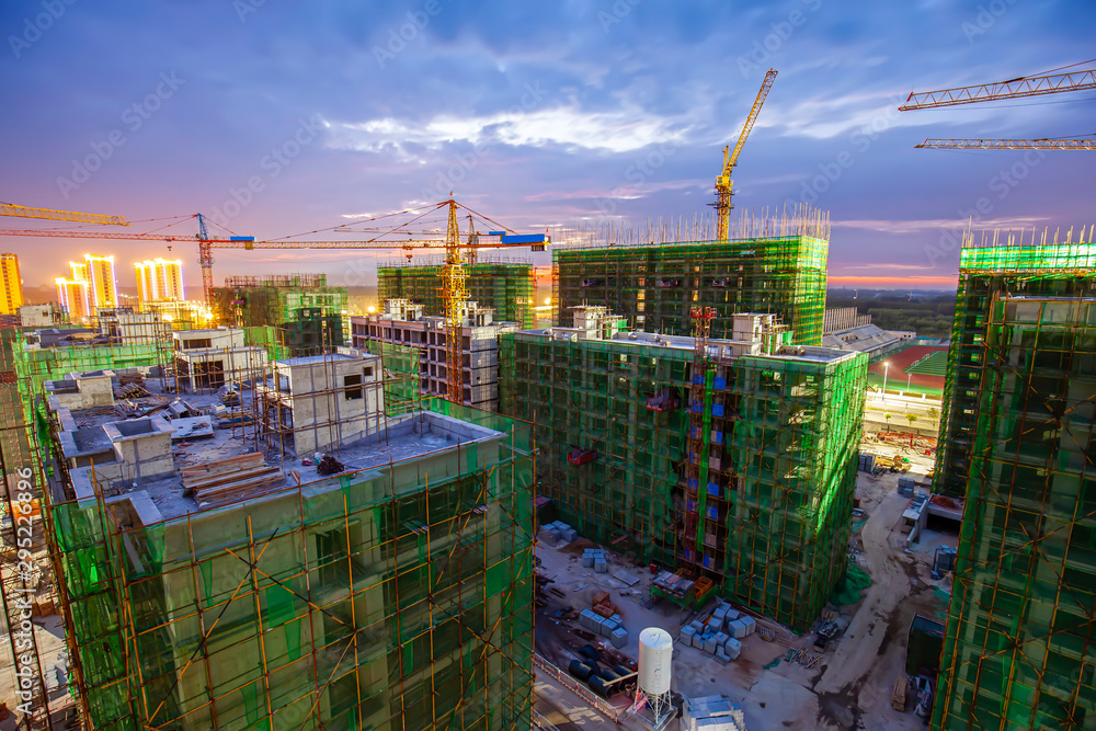 Fototapeta premium Tower cranes build residential buildings at nigh