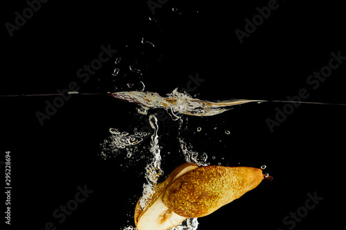 ripe pear halves falling deep in water with splash isolated on black