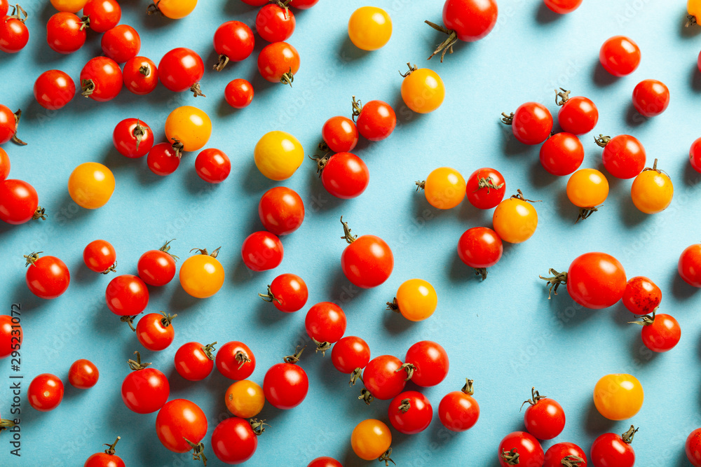 Red and yellow cherry tomatoes on blue background. Fresh bright organic vegetables. Red and yellow cherry tomatoes on blue background. Fresh bright organic vegetables.