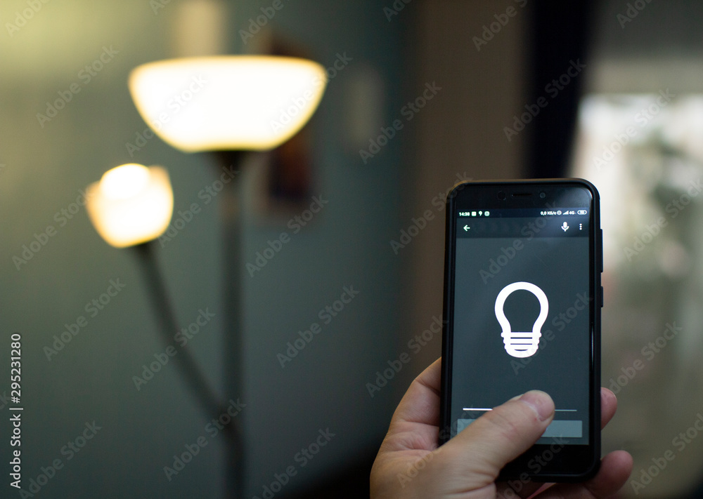 Smart home: man controlling lights with app on his phone.