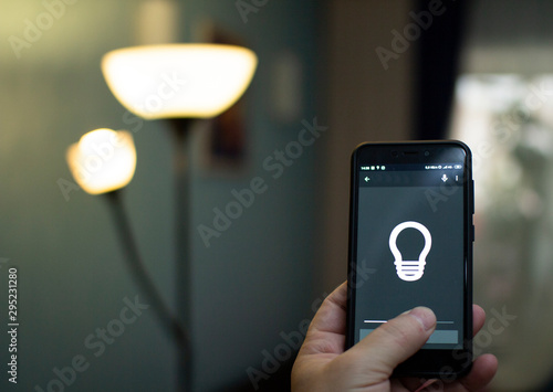 Obraz na płótnie Smart home: man controlling lights with app on his phone. w salonie