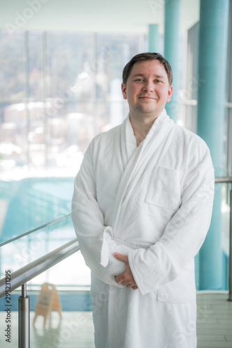 Man standing next to a pool in a robe and relaxing