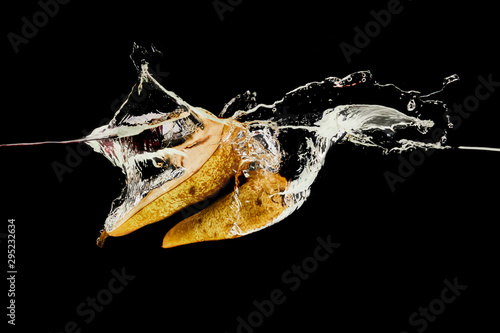 Fototapeta Naklejka Na Ścianę i Meble -  pear halves falling deep in water with splash isolated on black