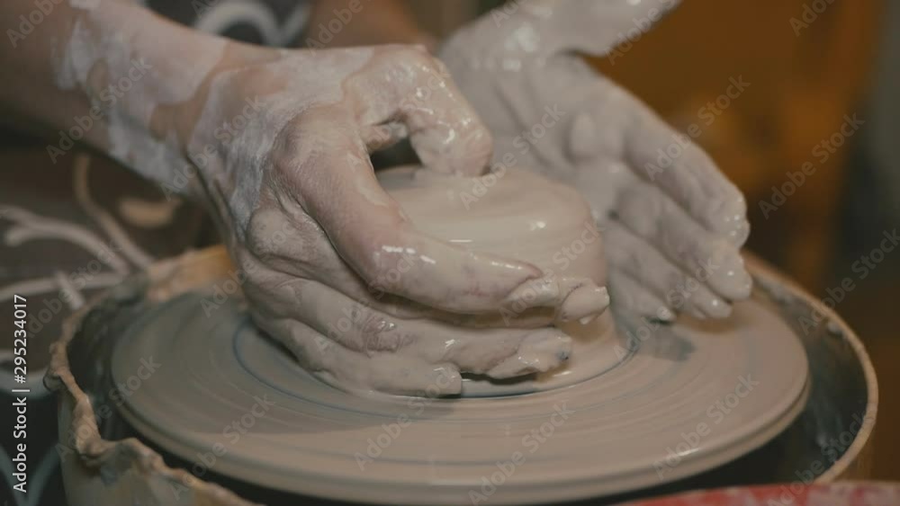 the potter forms an earthenware product on a pottery wheel. hands of a student of a potter the potter forms an earthenware product on a pottery wheel. hands of a student of a potter