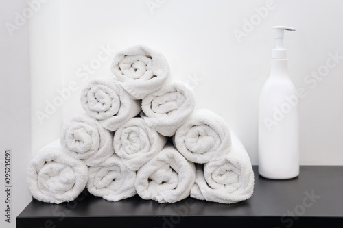 Rolled up white towels with cosmetic bottle. Soap bottle and white towels rolled on a table for spa.