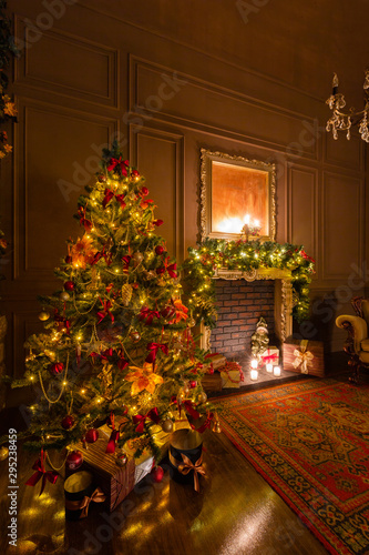 Christmas evening by candlelight. classic apartments with a fireplace  decorated tree  armchair.