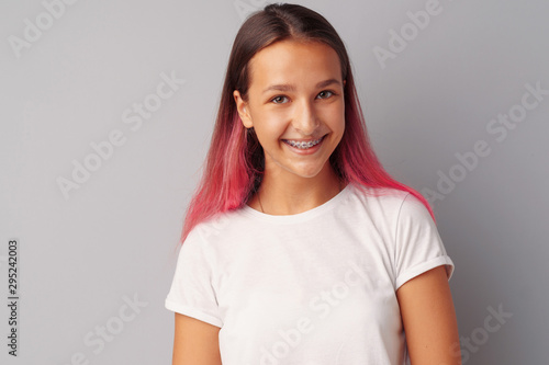 Young girl teenager with pink hair happy and smiling over gray background
