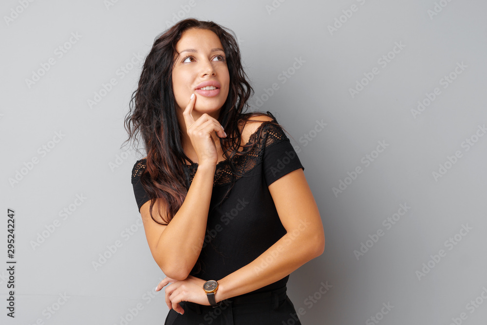Image of thinking young woman standing over a gray background. Image of thinking young woman standing over a gray background.