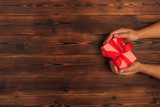 gift in female hands on a wooden background top view. - Image