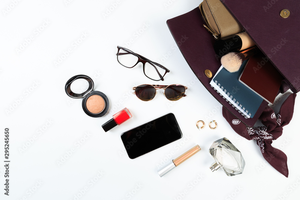 Fashion concept : Flat lay of purple leather woman bag open out with sunglasses and smartphone on white background.- Image Fashion concept : Flat lay of purple leather woman bag open out with sunglasses and smartphone on white background.- Image