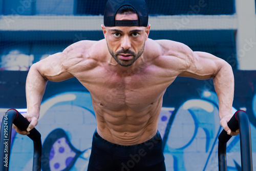 Fotografie Fitness man training calisthenics without shirt on the street
