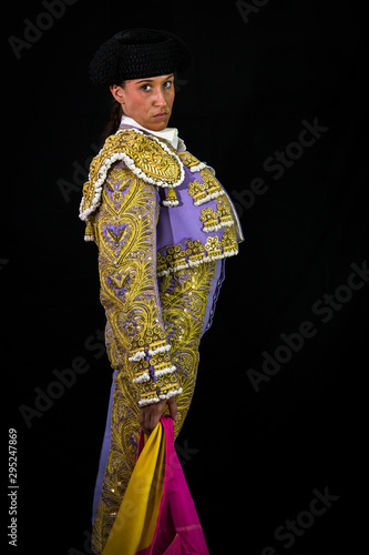 Woman bullfighter holding capote pink on black background