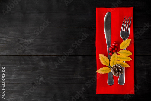 Thanksgiving autumn place setting with cutlery and arrangement of colorful fall leaves.