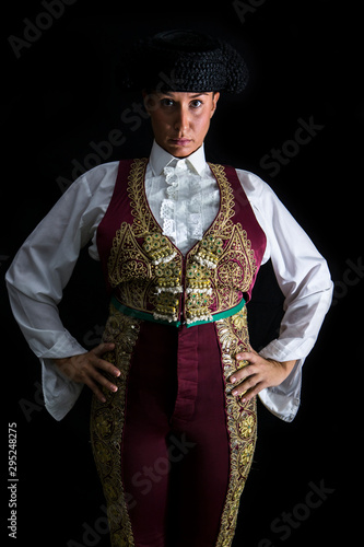 Woman bullfighter by dressing in a costume of old lighting on a black background