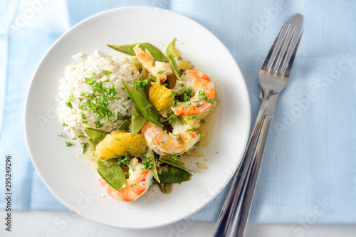 fried tiger prawn shrimp dish with sugar peas  onion  oranges and rice  high angle view from above  copy space